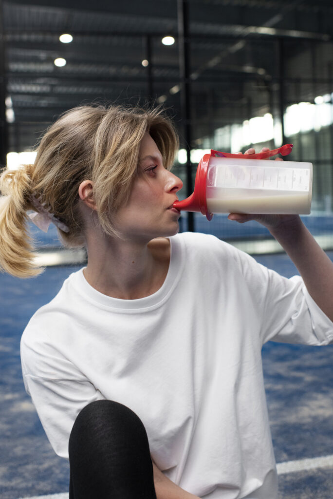 woman drinking her supplements in gym